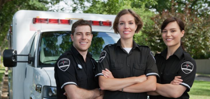 a couple of paramedics standing in front of a ambulance