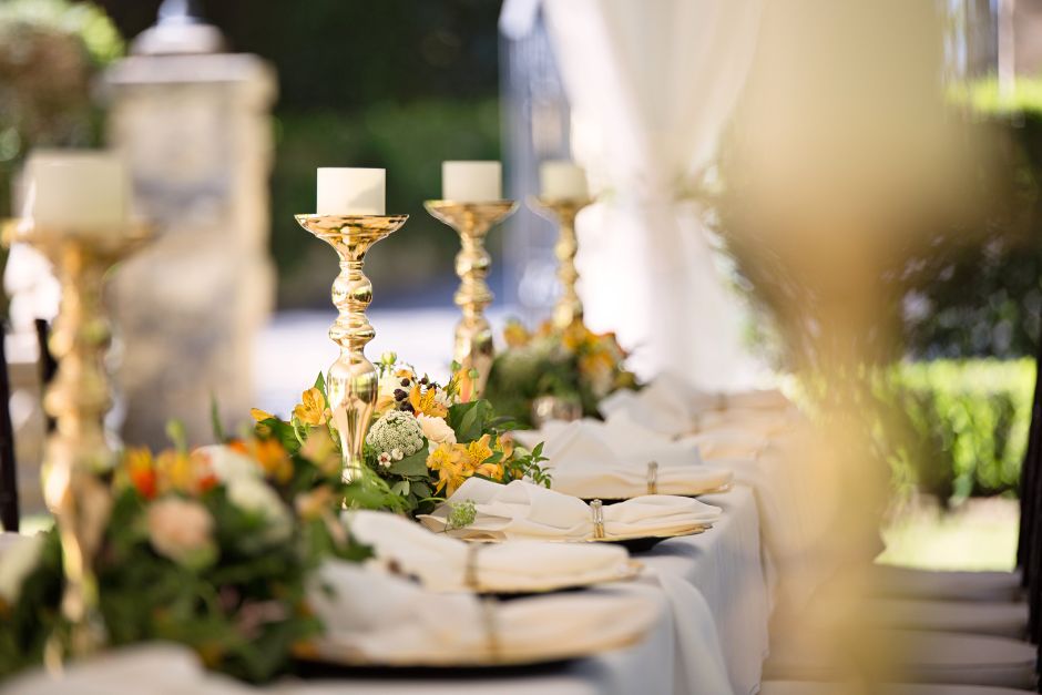 table set with brass candle sticks plates, and flowers